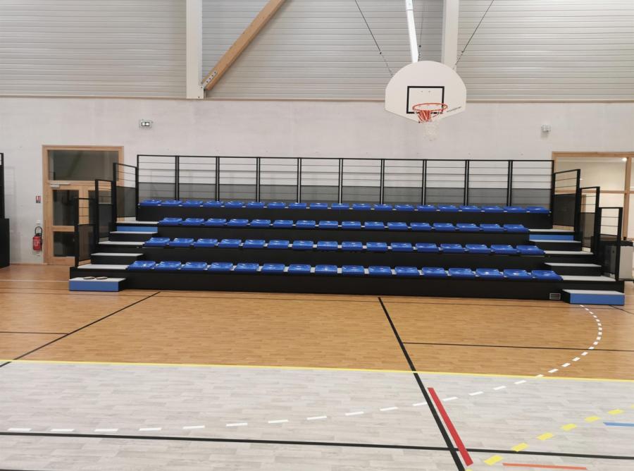 Dieselbe Dreifeldhalle mit ausgefahrener Teleskoptribüne und blauen Sitzschalen